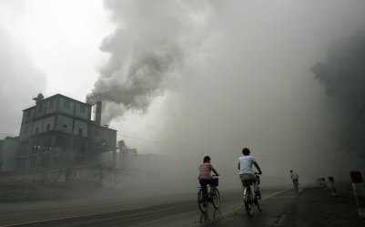 (FILES) This picture taken 18 July 2006 shows cyclists passing through thick pollution from a factory in Yutian, 100km east of Beijing in China's northwest Hebei province. China has no plans to radically change its reliance on coal and other dirty fuels despite already feeling the impacts of global warming, a leading Chinese meteorologist said 06 February 2007. In the first official Chinese response to a stark UN report issued last week on climate change, Qin Dahe said China lacked the technology and financial resources for a wholesale conversion to cleaner energy sources. AFP PHOTO/Peter PARKS/FILES (Photo credit should read PETER PARKS/AFP/Getty Images)
